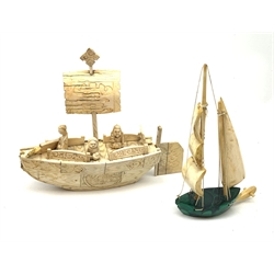 A Japanese carved ivory model of a sailing boat, surmounted by three carved figures (a/f), L22.5cm, together with a smaller sail boat with malachite hull and ivory sails and rudder, H18cm. 