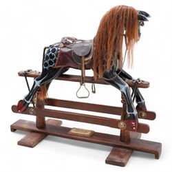 Retailed by Harrods - 'Millennium Limited Edition' rocking horse, dappled black finish with leather saddle and stirrups, on trestle base with turned pedestals, brass plaque inscribed 'Special Millennium Limited Edition To Mark Year 2004 Serial No. 325' 