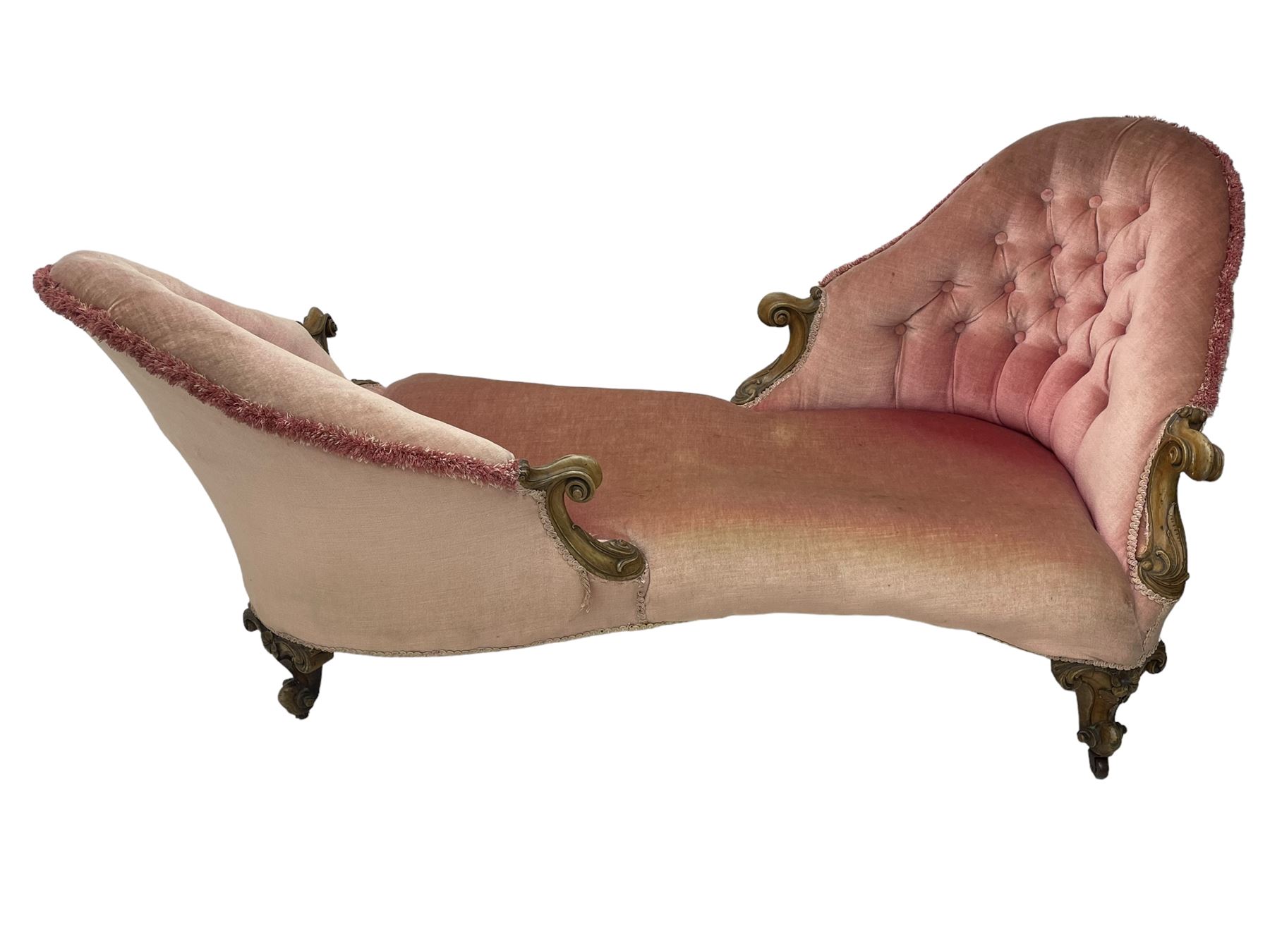 Victorian walnut framed tete-a-tete loveseat, scrolled arm terminals with moulded foliate decoration, buttoned backs and sprung seat upholstered in pale pink velvet, raised on cabriole supports with applied flower heads and scroll feet terminating to ceramic castors