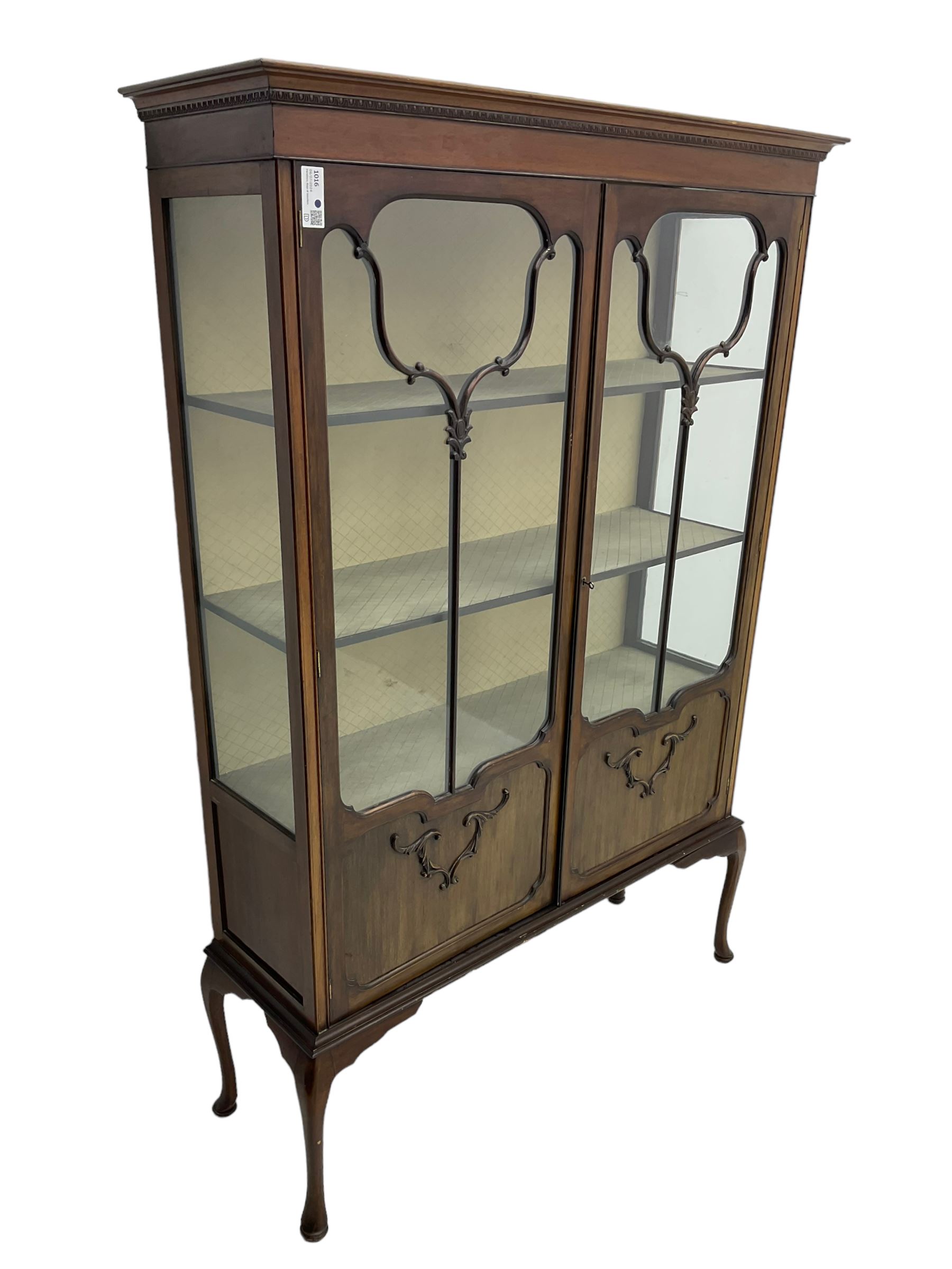 Early 20th century mahogany straight-front display cabinet, projecting moulded cornice over two astragal glazed doors with lower panels, on cabriole supports 