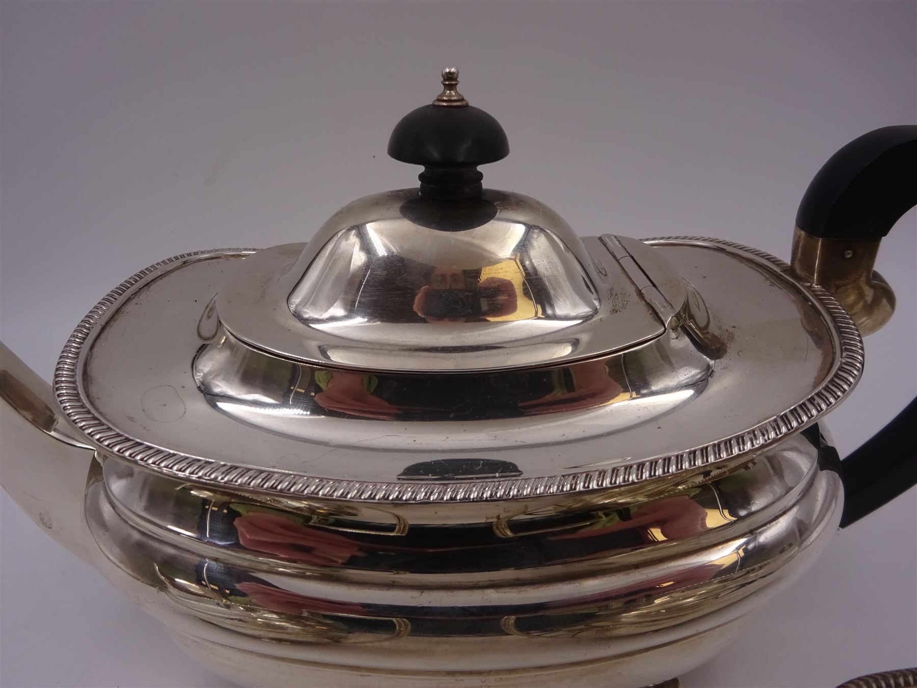 Silver three piece tea service, comprising teapot, twin handled open sucrier and a milk jug, all of oval part fluted form and upon four bun feet, the teapot with black plastic handle and finial, hallmarked S Blanckensee & Son Ltd, Chester 1930, teapot H16cm