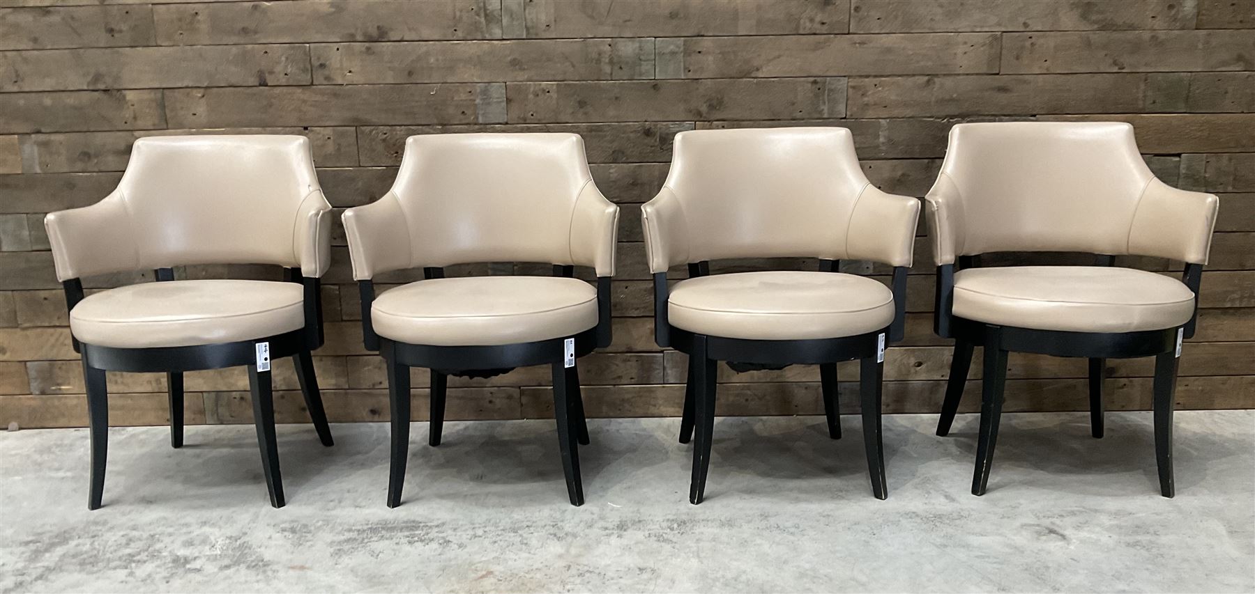 Four ebonised framed tub shaped armchairs, upholstered in beige fabric