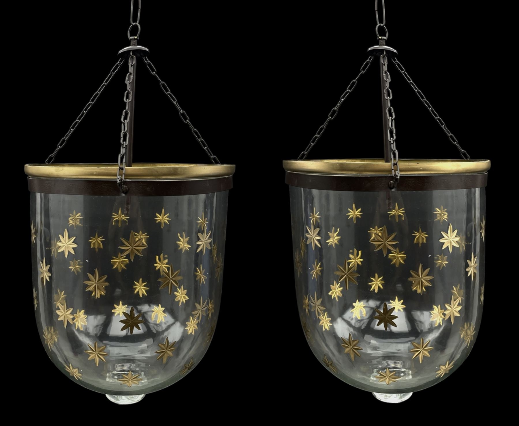 India Jane Interiors - pair of glass hanging lanterns, clear glass bell jars decorated with gold starburst patterns, each topped with a wide glass dish and suspended by three brass chains, the rim of each bell jar accentuated with a brass band, black metal hooks with a dragon head motif attach the chains to the rim