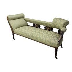 Late Victorian walnut salon settee or chaise lounge, double-ended with rolled back and curved end, upholstered in light aquamarine fabric with raised repeating lozenge pattern, decorated with laurel leaf wreaths and urns, three pierced splats carved with curled leaves, inlaid with dolphins and scrolled foliate motifs in simulated ivory and boxwood, on tapering ring turned supports with brass and ceramic castors (L166, D60, H70cm); together with matching tub-shaped armchair (W61cm, H73cm, D66cm)  