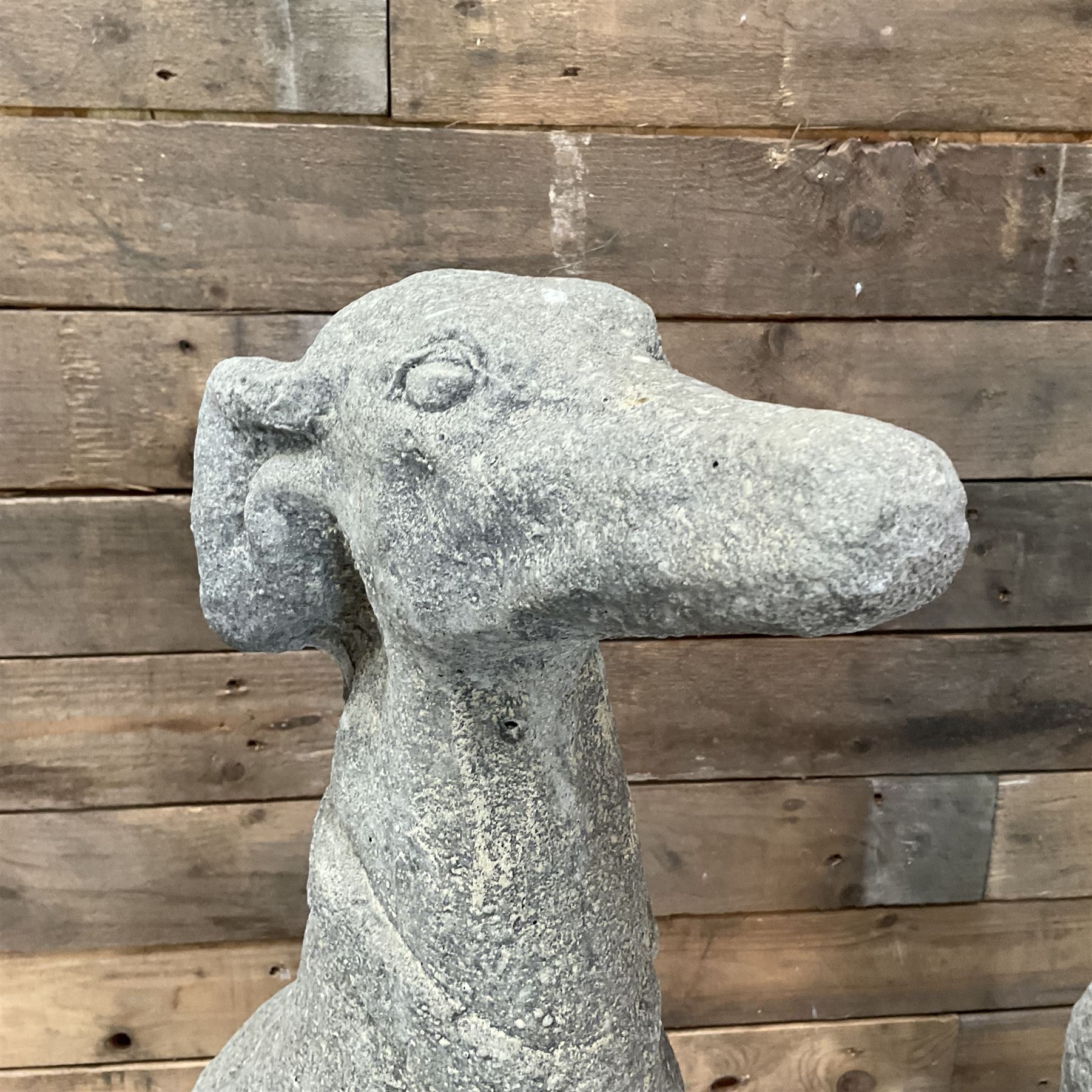 Pair of cast stone French lurchers, seated pose, on shaped plinth