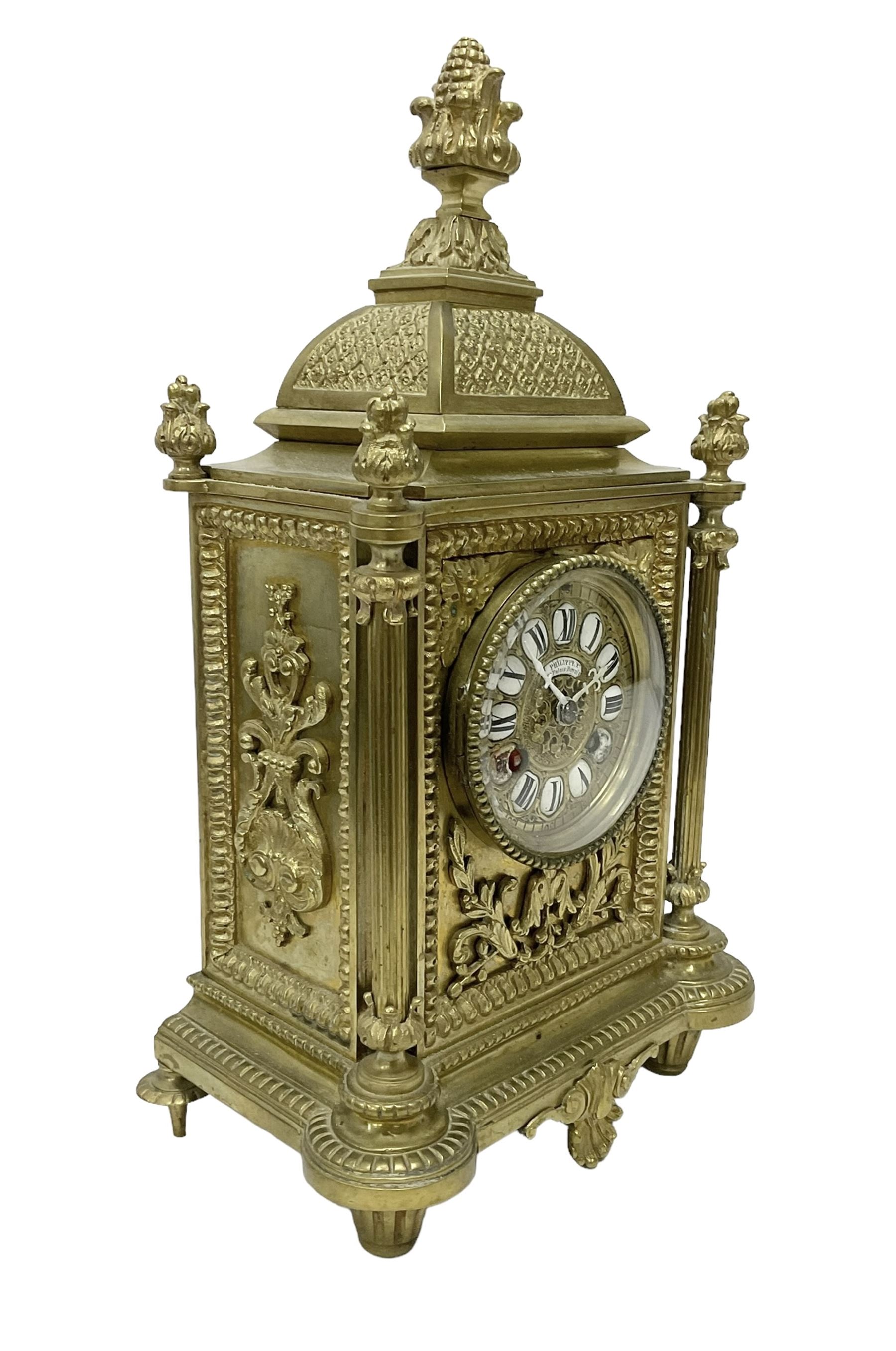 French - Brass cased 8-day mantle clock c1880, with a domed top surmounted by a pineapple finial, four reeded pilasters to the corners and raised on tapered feet, with a conforming dial with cartouche numerals, fleur-di -Lis hands and the name, Phillippe, 66 Palais Royal, Paris, twin train countwheel striking movement sounding the hours and half-hours on a bell.  With pendulum and key. 
