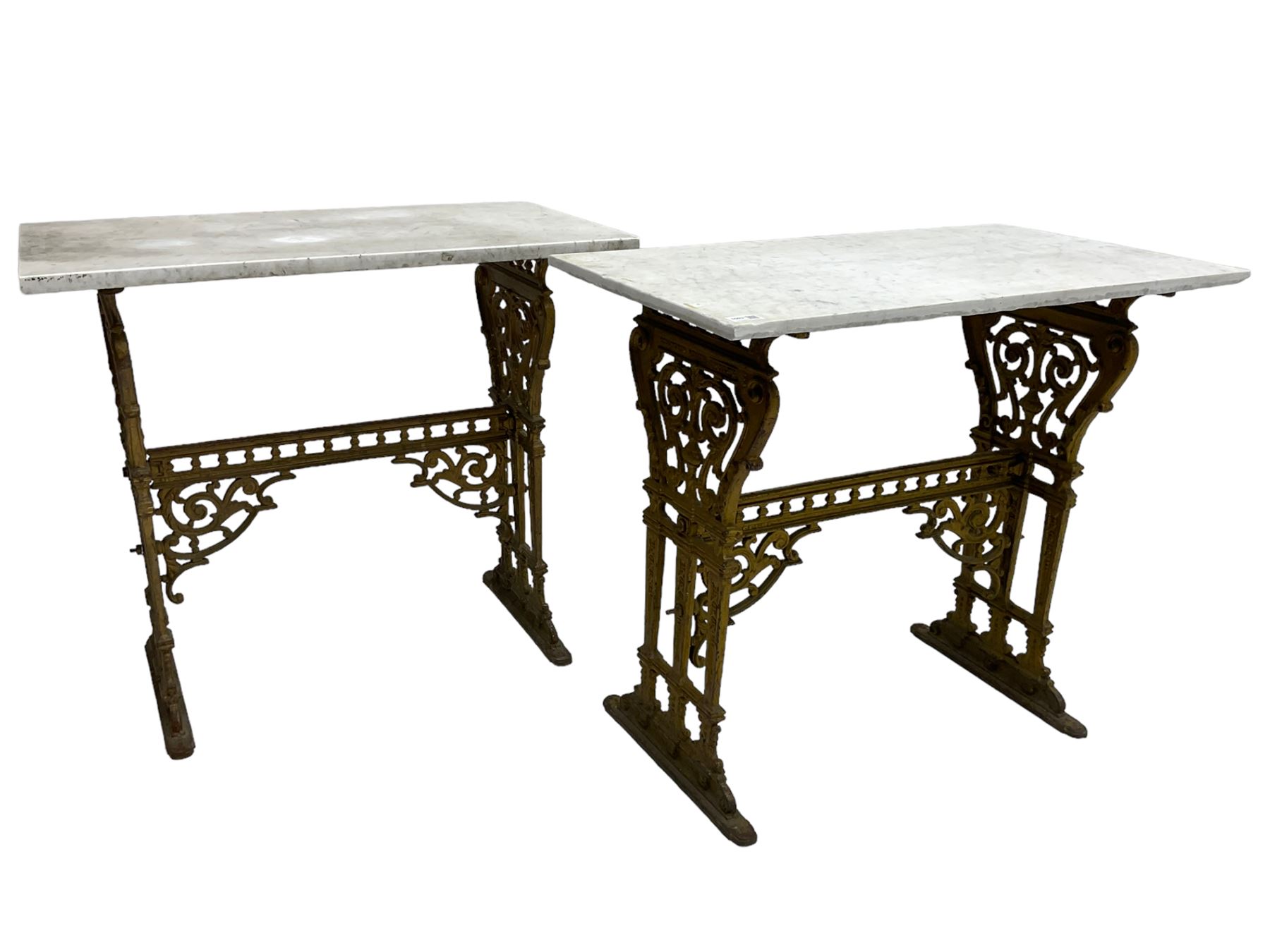 Pair of 19th century cast iron entrance tables, rectangular marble top over ornate gilt bases with scrolling foliate design and sledge feet, united by balustrade stretcher with scroll spandrels