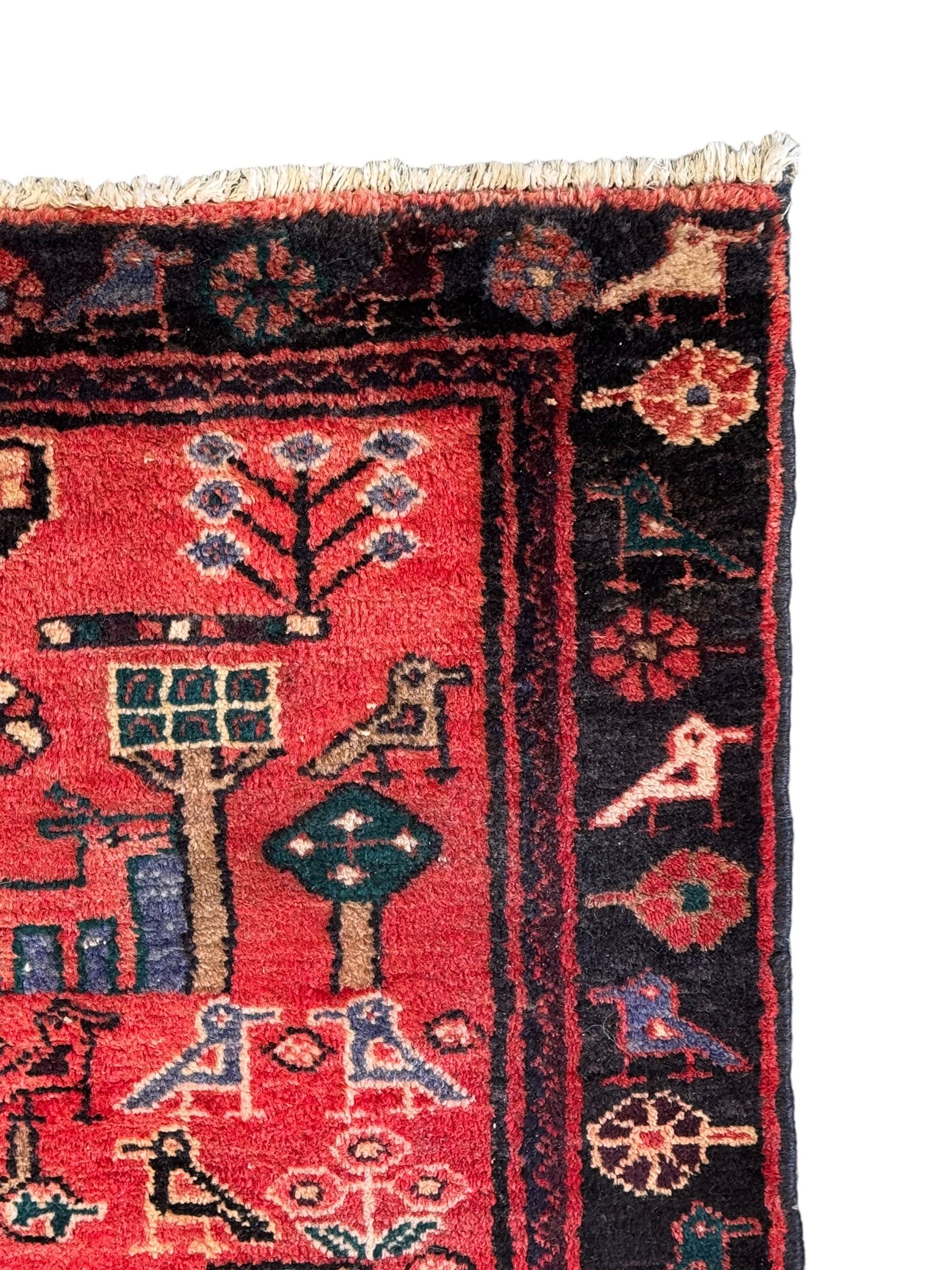 Persian crimson ground runner, the field decorated with stylised tree and animal motifs, indigo ground border decorated with alternating stylised flowerhead and bird motifs 