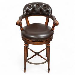 Pair of hardwood-framed bar stools, revolving tub seat with buttoned back rest and upholstered seat in brown leather, reed moulded seat rail over four lobe carved tapering supports, united by metal foot rest and x-framed stretchers 