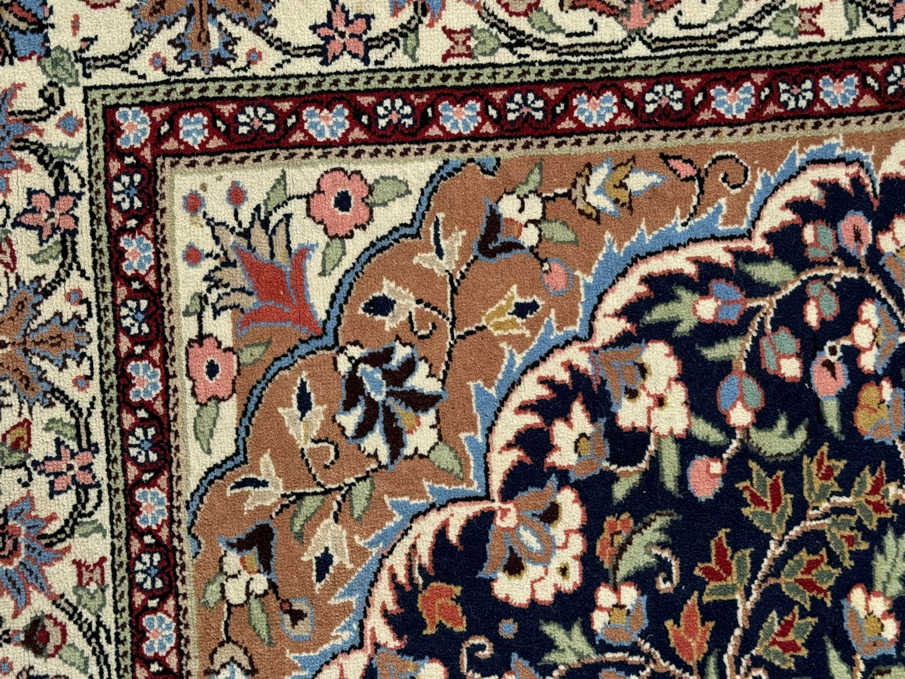 Indo-Persian indigo ground rug, the floral design peach medallion surrounded by trailing and interlaced branches and flower heads, the main border decorated with repeating stylised plant motifs within floral guard stripes 