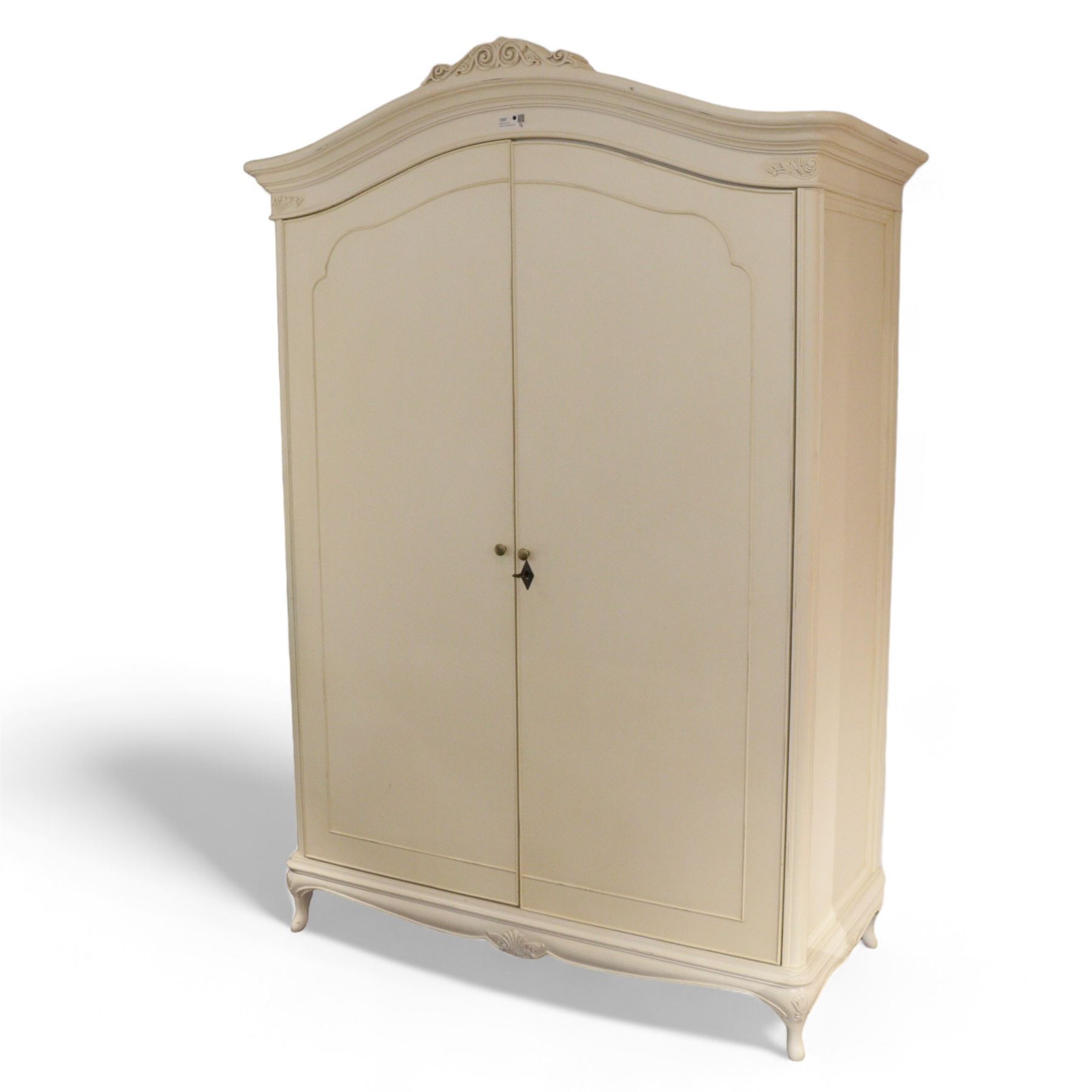 French design cream painted Armoire, foliate scroll decorated pediment over two doors, fitted with hanging rails and shelves, on cabriole feet