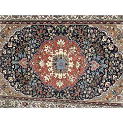 Indo-Persian indigo ground rug, the floral design peach medallion surrounded by trailing and interlaced branches and flower heads, the main border decorated with repeating stylised plant motifs within floral guard stripes 