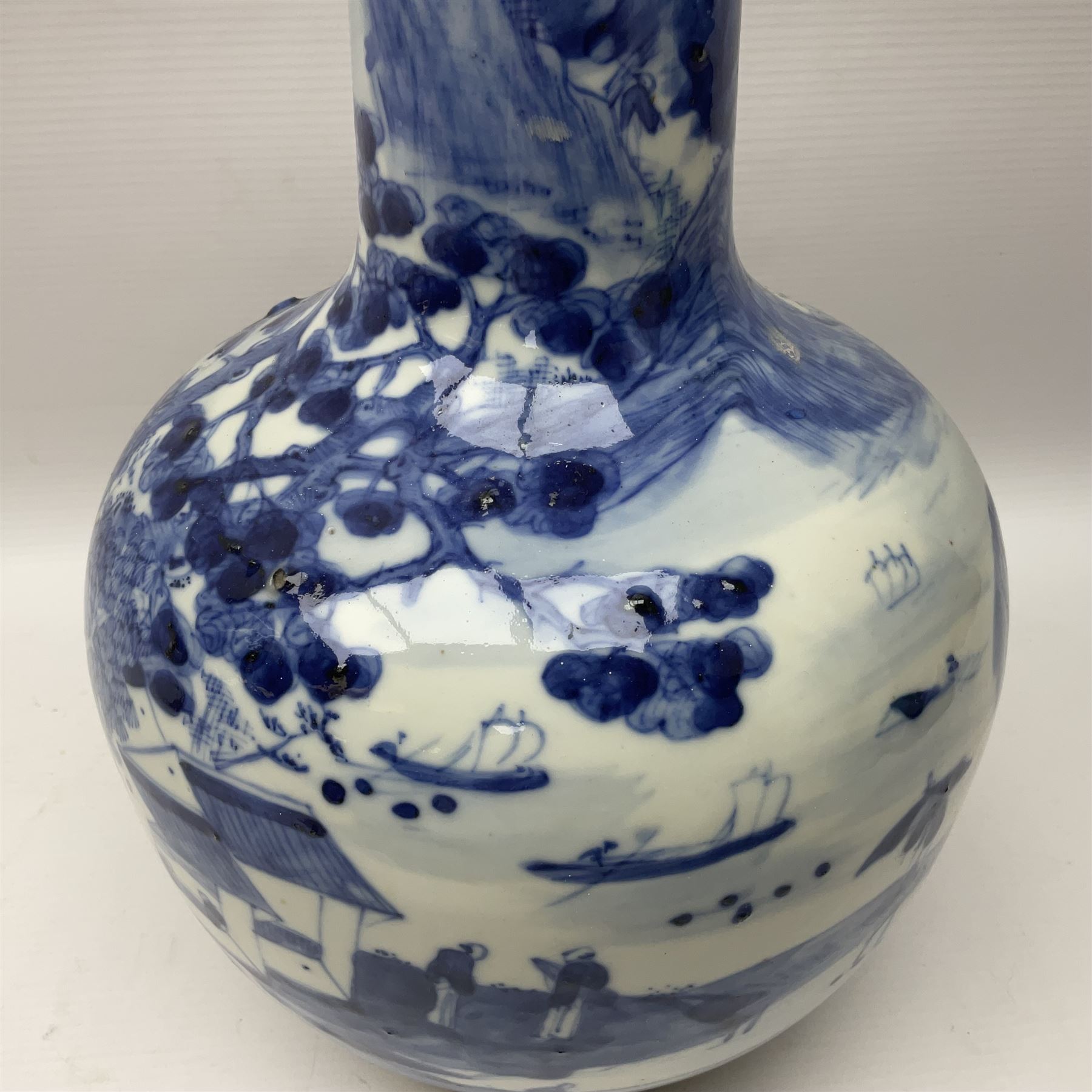 Late 18th/early 19th century Chinese blue and white bottle vase, decorated with a landscape scene containing dwellings, prunus and pine trees, boats and bridges, and populated with figures, with character mark beneath, H35cm