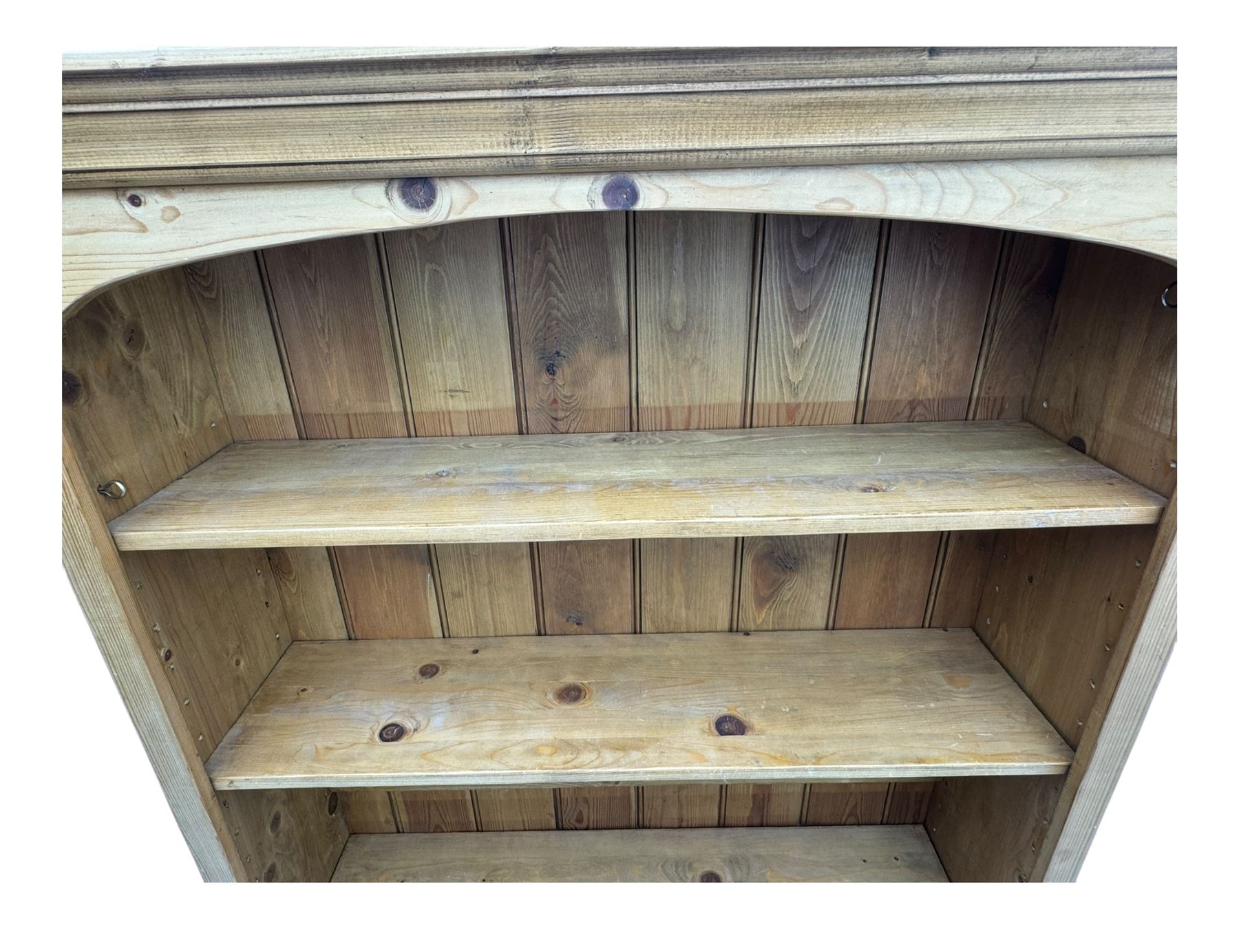 Pine open bookcase, projecting moulded cornice over arched frieze, fitted with four adjustable shelves, on plinth base