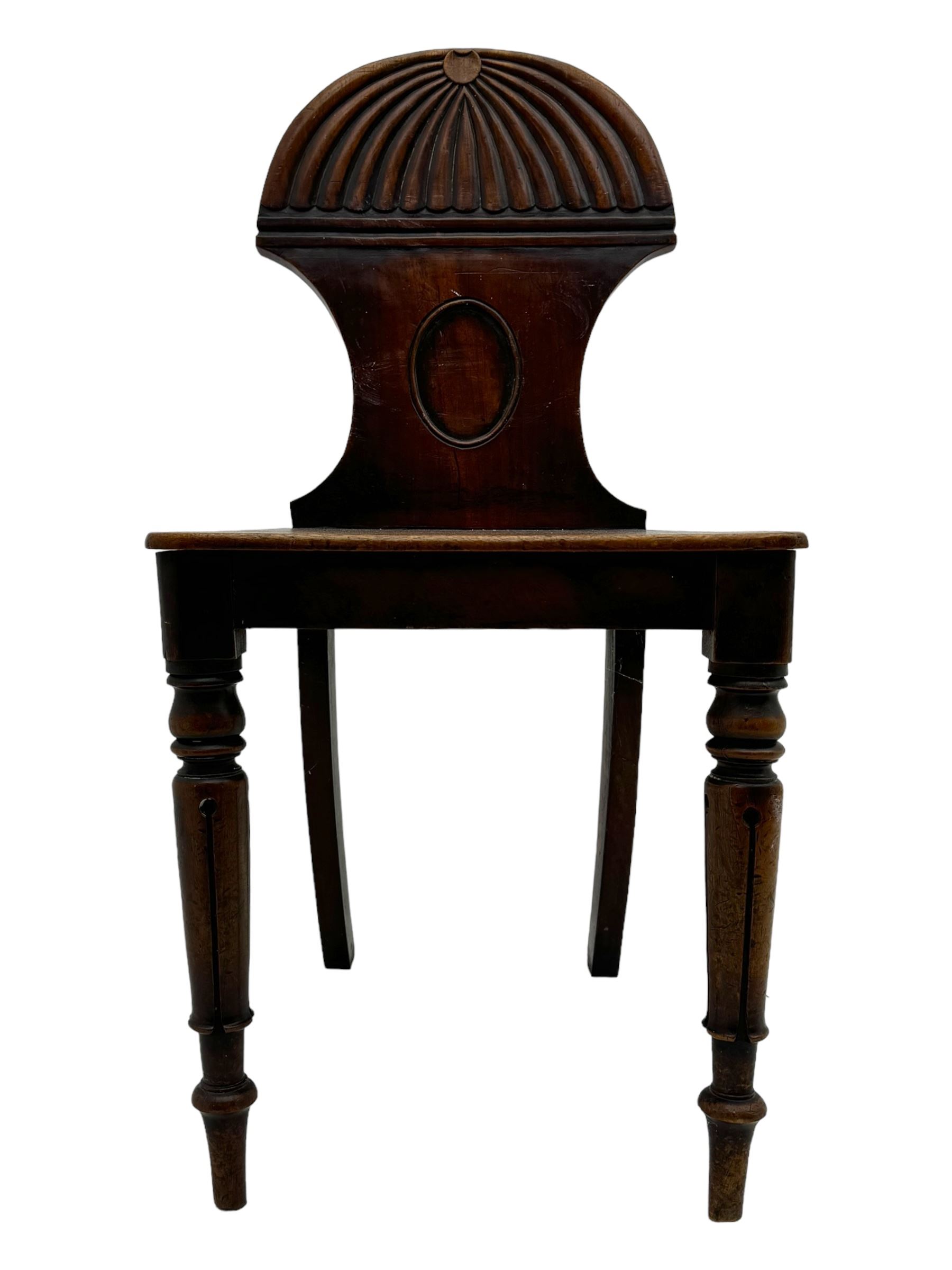 Regency mahogany hall chair, the carved back with shell motif and oval medallion, supported by turned front legs and splayed rear legs