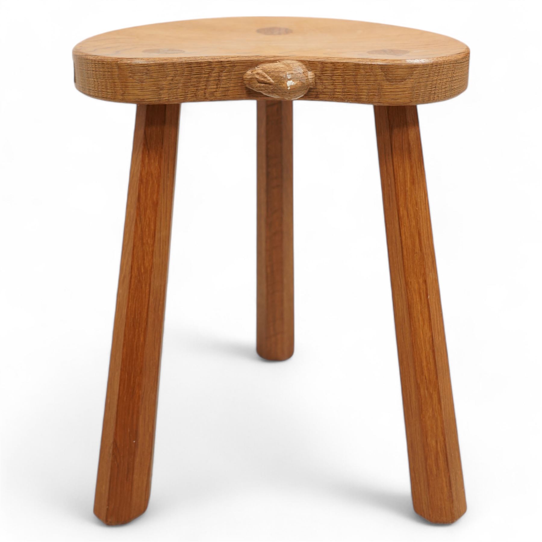 Rabbitman -  oak milking stool, dished kidney shaped top, on three tapered octagonal supports, carved with rabbit signature, by Peter Heap, Wetwang