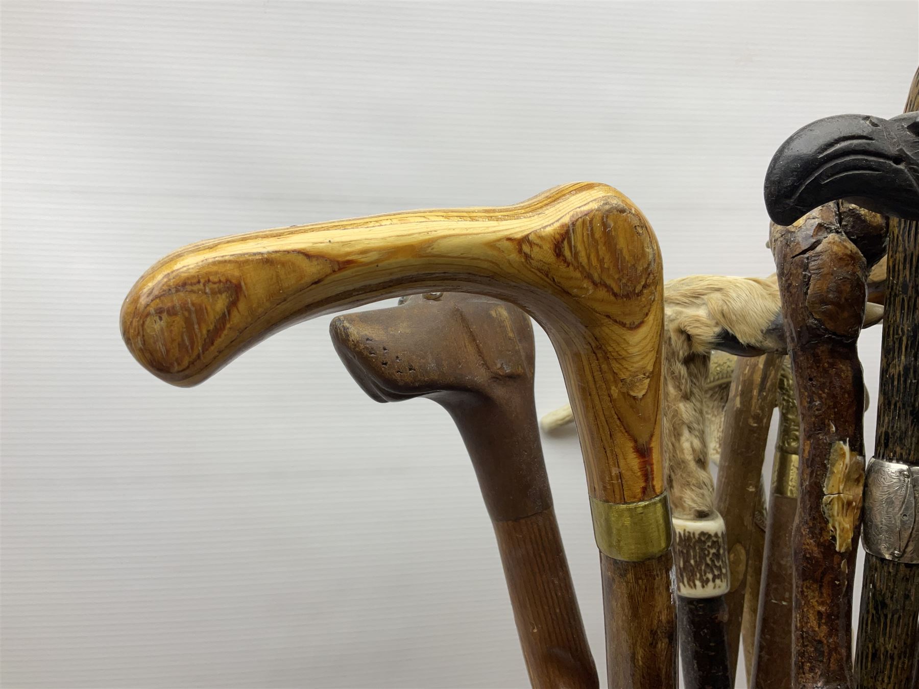 Oak barley twist stick stand, with a collection of walking sticks including examples with carved pommels, horn handles, silver collar etc, together with brass stick stand 