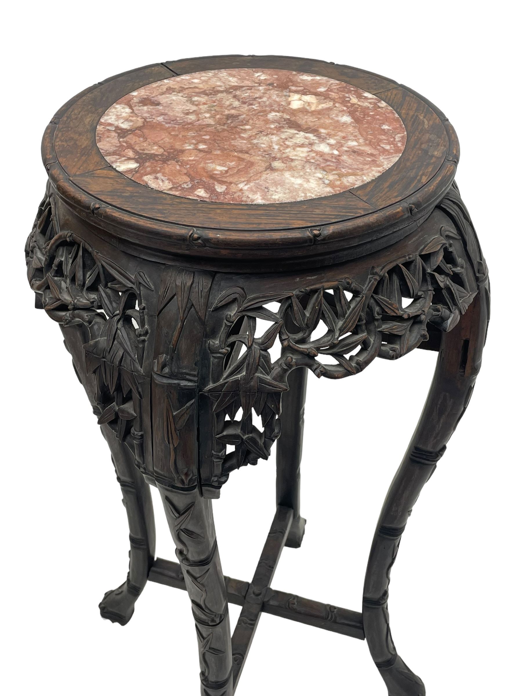 Early 20th century Chinese hardwood plant stand, circular top with marble inset, carved and pierced with interlacing foliage, on leaf carved supports united by x-framed stretchers