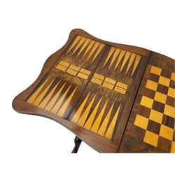 Victorian inlaid figured walnut games table, the serpentine fold-over top inlaid with scrolling foliate decoration, the top opens to reveal cribbage, backgammon and chess boards, single drawer over sliding storage well, on twin pillar supports united by double turned stretchers, on foliage carved out-splayed supports with brass and ceramic castors 