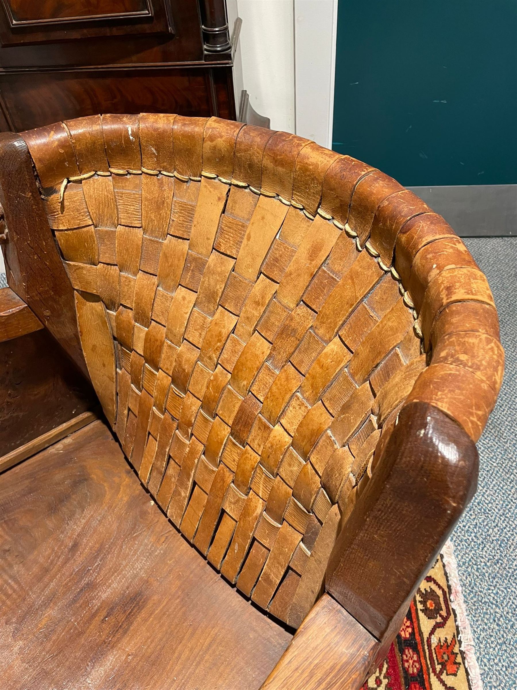 Mouseman - unusual circa. 1930s adzed oak tub-shaped armchair, barrel-back with woven leather, the upright carved with mouse signature, figured panelled sides enclosing panelled seat, arched seat rail, stile supports with block feet on castors, by the workshop of Robert Thompson, Kilburn  

Notes: made by apprentice Graham Hayes (1914-1943). Hayes went on to become a founding member of the Small Scale Raiding Force (SSRF), a special commando unit under the Special Operations Executive (SOE), established by Winston Churchill in 1940. Tragically, he was captured in 1942 and held prisoner by the Gestapo until his execution in 1943. Recently, Hayes has been featured in Guy Ritchie's film 'The Ministry of Ungentlemanly Warfare' under the name 