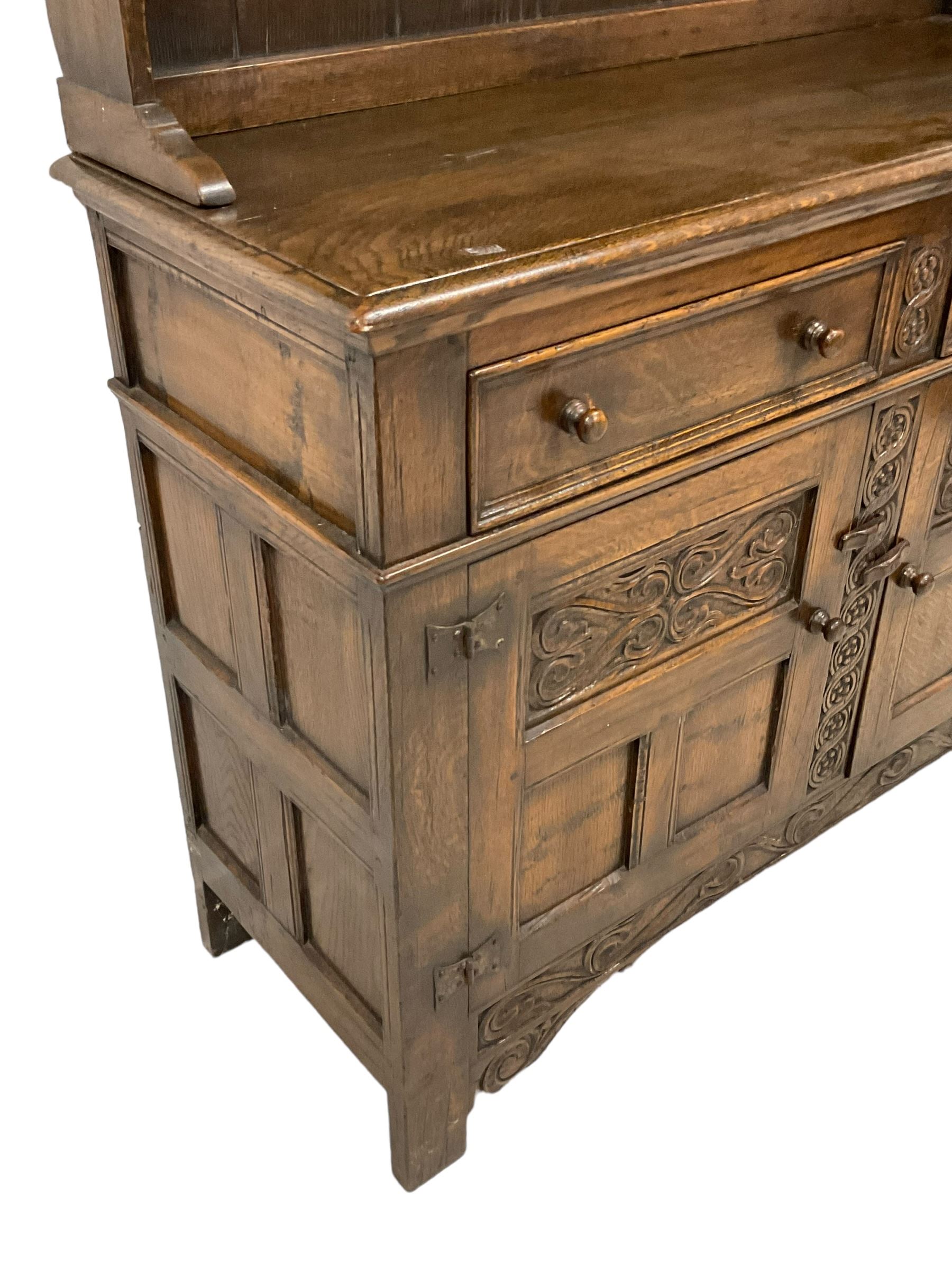 Georgian design oak dresser, two-tier plate rack with shaped aprons, the base fitted with two fielded moulded drawers, over two panelled cupboards carved with scrolling acanthus leaves, with guilloche carved central upright, on stile feet