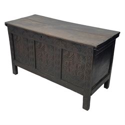 18th century oak blanket box, moulded and chip carved hinged lid, lunette carved cresting rail over triple panelled front carved with stylised leaf and scroll decoration, interlocking S-scroll carved upright rails, panelled sides and back, on stile supports 