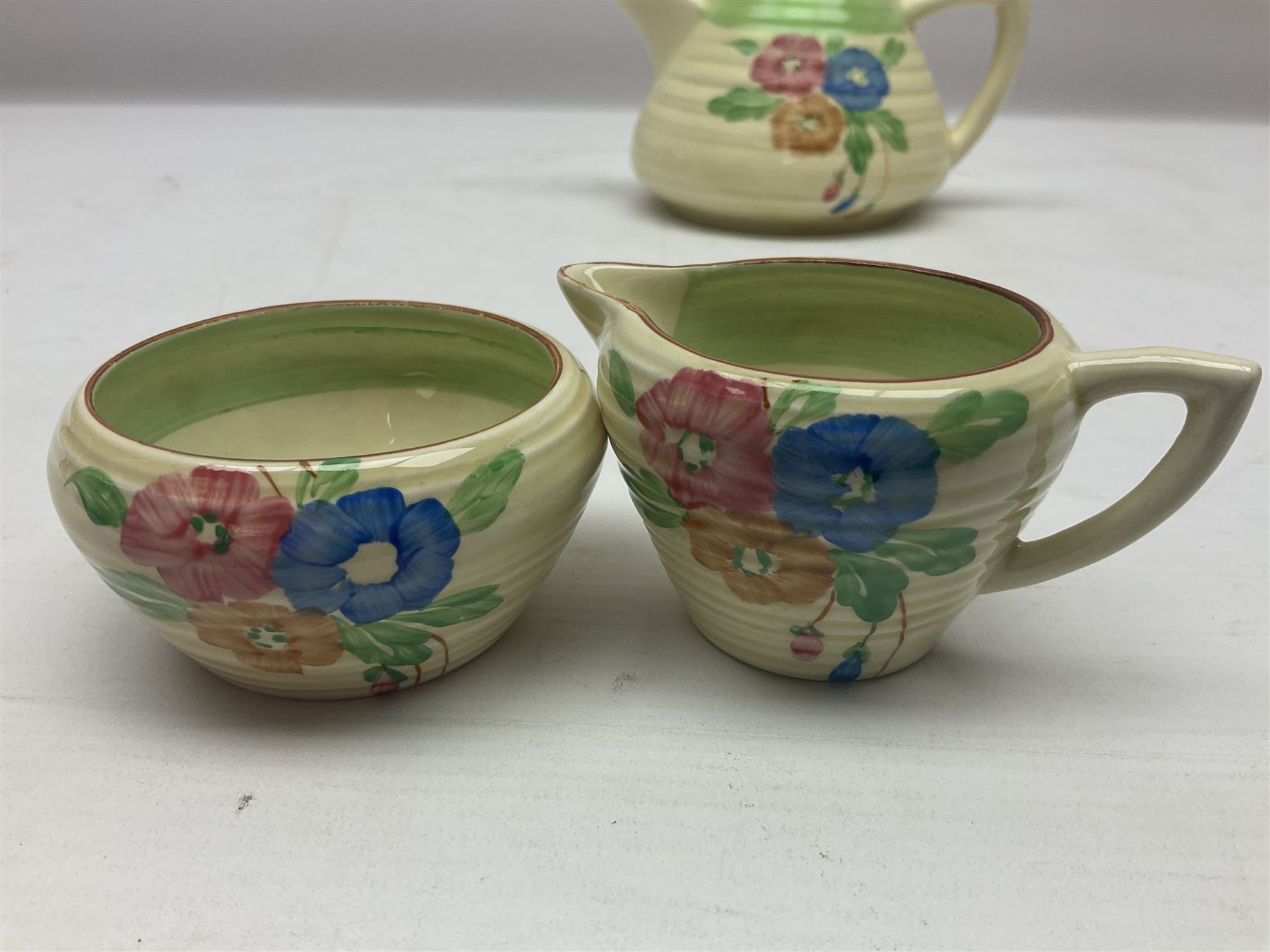 Clarice Cliff for Newport Pottery three piece tea service, in Nosegay pattern, comprising teapot, milk jug and sugar bowl, with printed mark beneath, teapot H12.5cm