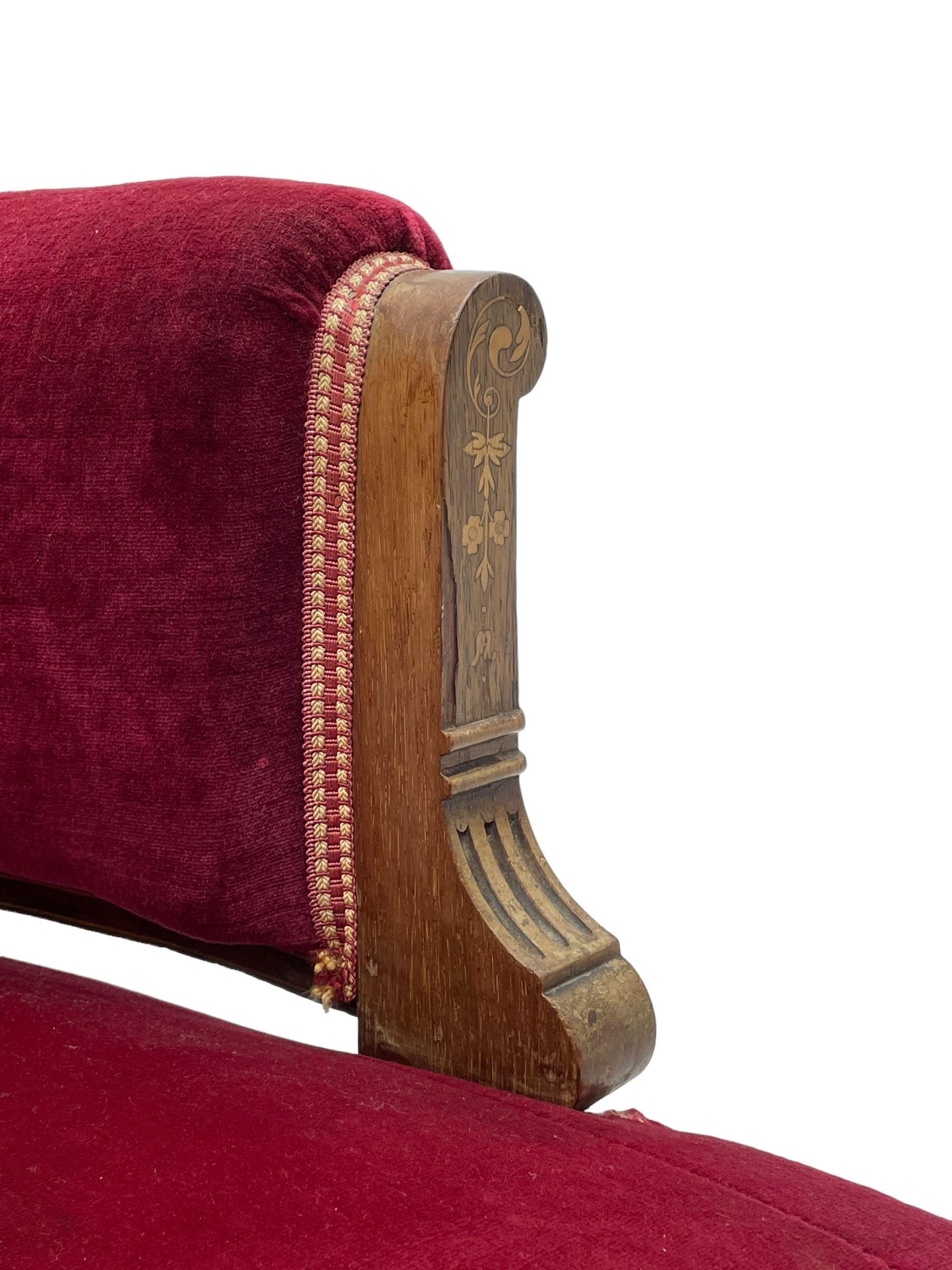 Late Victorian inlaid walnut two seat settee, the shaped cresting rail decorated with foliate inlays and boxwood stringing, upholstered in crimson velvet with sprung seat, raised on turned and fluted supports with ceramic castors