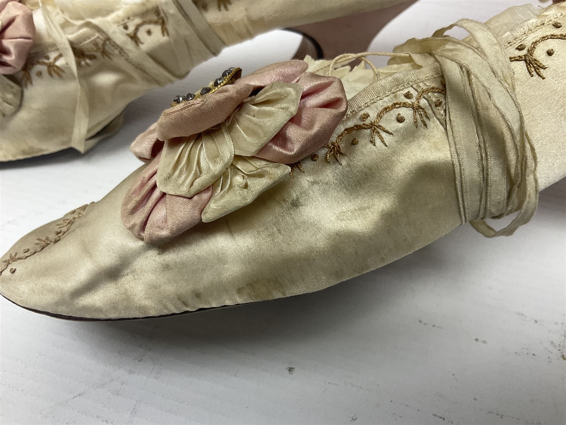 Pair of 19th century ivory silk satin ladies shoes, with rosette to the vamp, with pink silk satin heel, L23cm