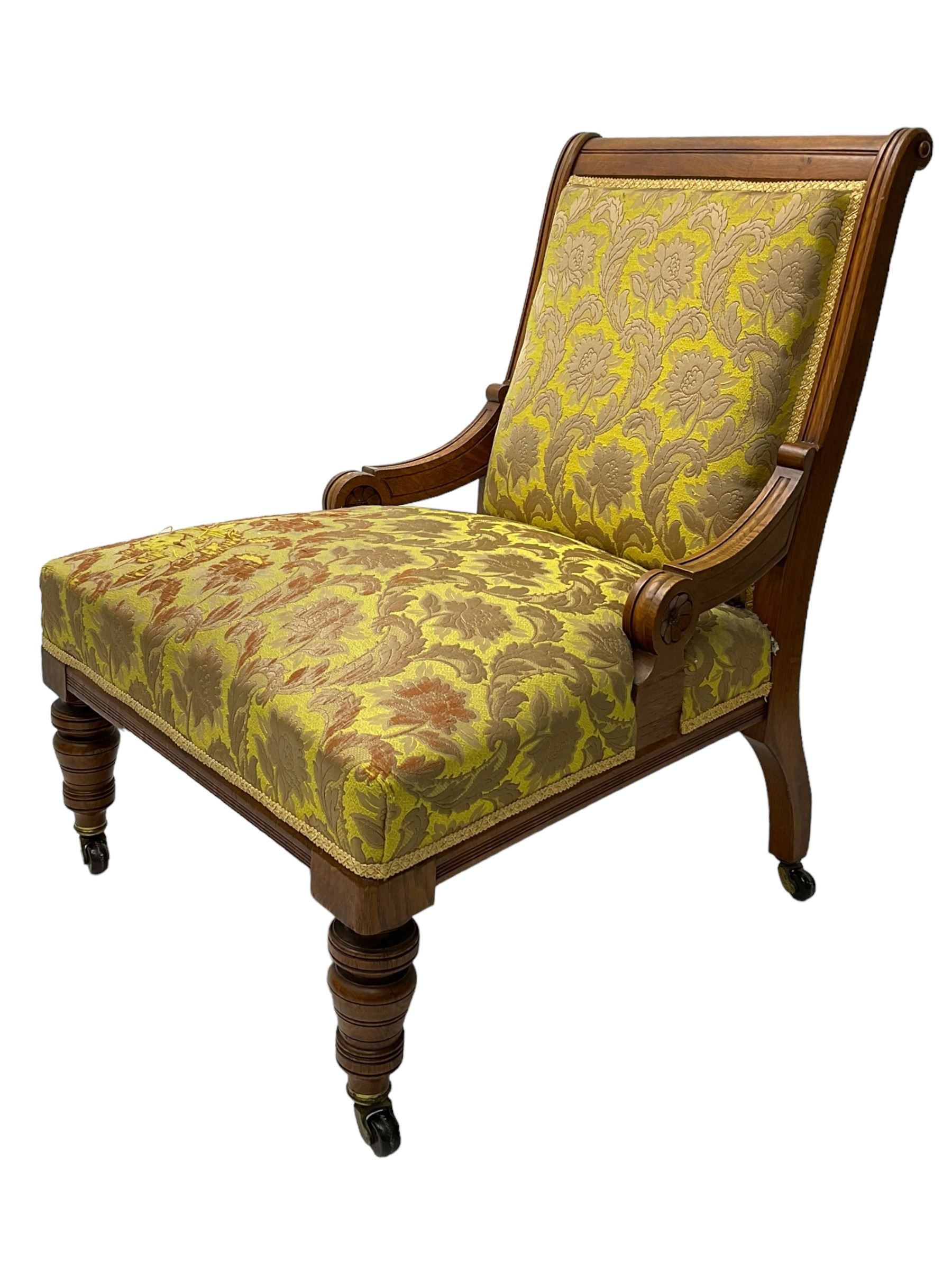 Late Victorian oak nursing chair, moulded frame with flower head carved roundels, upholstered in floral pattern fabric, on turned front feet with brass and ceramic castors 