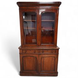 Victorian mahogany bookcase on cupboard, projecting cornice over two glazed doors, the lower section fitted with two drawers and two panelled cupboards, on moulded plinth base 