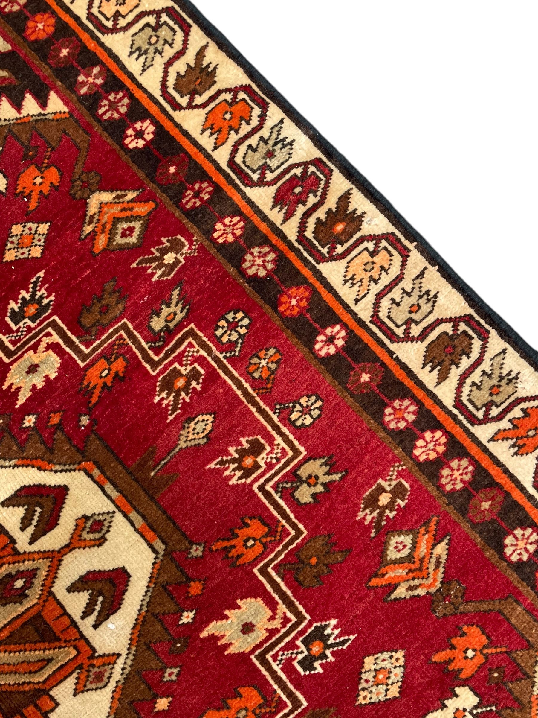 Persian crimson ground rug, the field decorated with three medallions within stepped borders, decorated all over with small stylised plant motifs, trailing flower head outer band and floral pattern border 