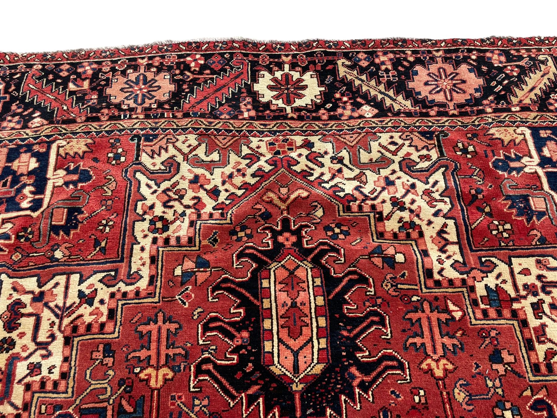 Persian Heriz red ground carpet, large central eight point medallion with projecting palmettes surrounded by small geometric motifs, decorated profusely with hooks, rosettes and animals, the busy border decorated with stylised foliate motifs within guard stripes 