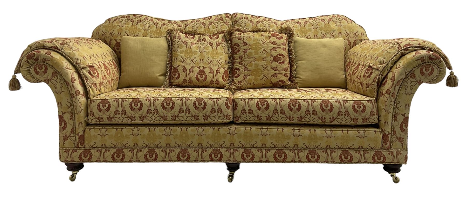 Steed Upholstery Ltd. - 'Lincoln' three-seat sofa upholstered in gold 'Olympia' floral pattern corded and tasselled fabric, together with scatter cushions and arm covers, on turned feet with brass castors