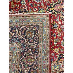 Persian Kashan crimson ground carpet, floral design central medallion surrounded by trailing leafy branches and stylised plant motifs, multi-band border with repeating floral design