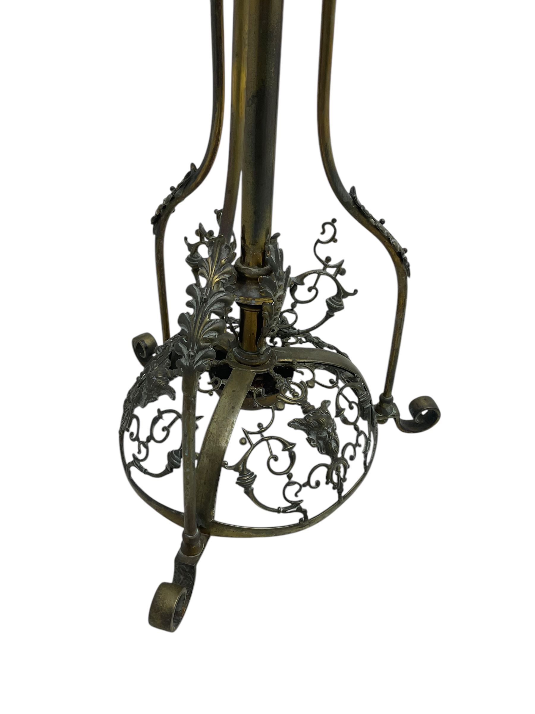 Victorian brass converted oil lamp stand, telescopic stem with scrolled uprights terminating to scrolled feet, dished base decorated with scrolling cast metal work and grotesque masks 