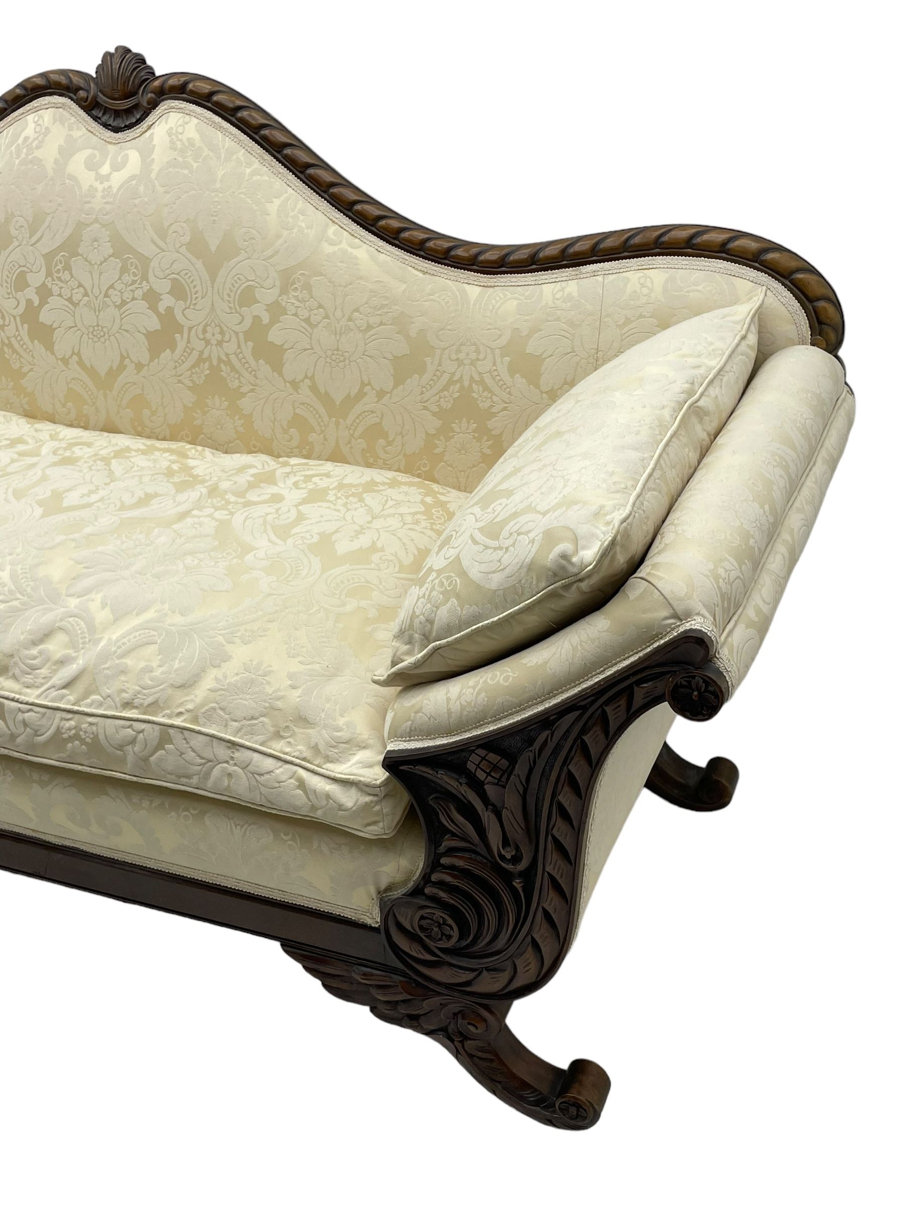 Victorian design walnut framed settee, shaped camelback with gadroon carved edge and central feather motif, upholstered in cream damask fabric with scrolling floral pattern, S-scroll arm facias carved with flower head and curled leaves, feather carved C-scroll splayed feet 