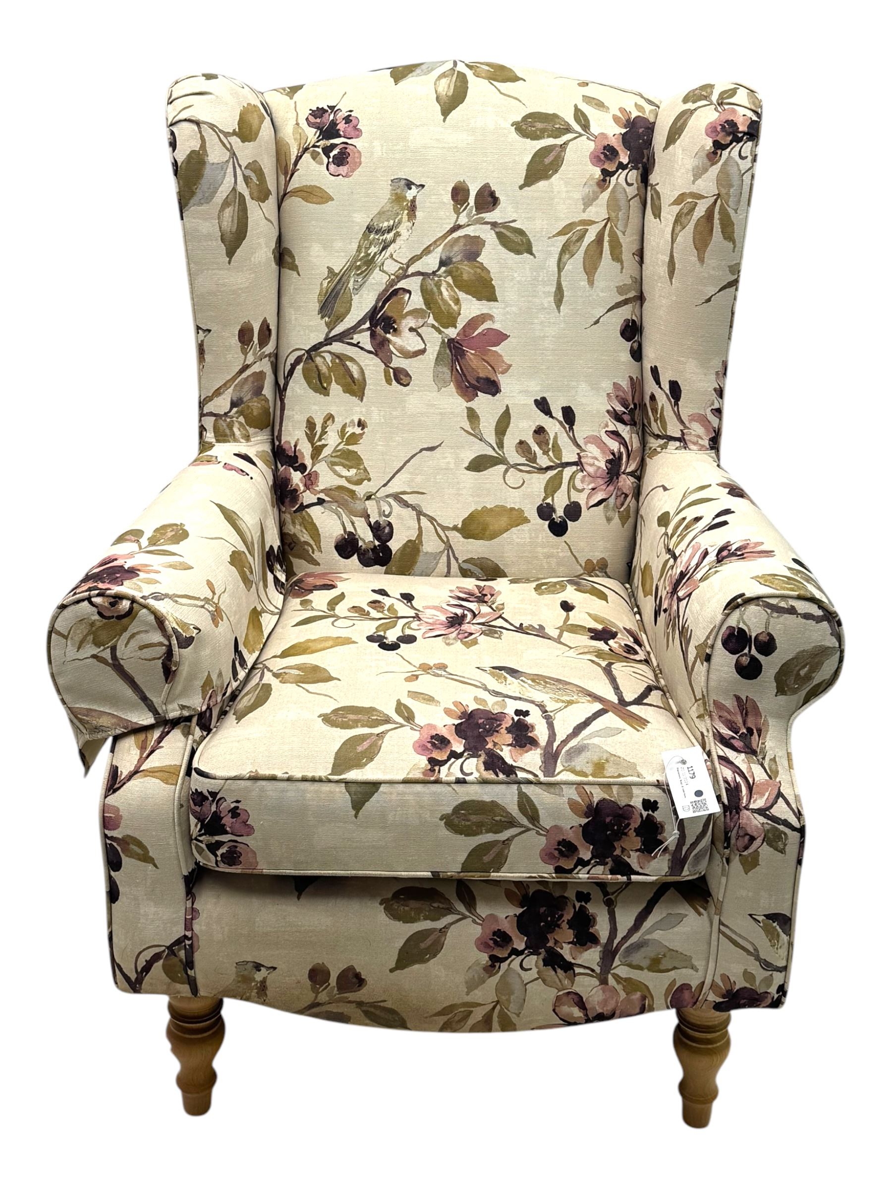 Hardwood-framed wingback armchair, upholstered in cream floral pattern fabric, on turned front feet