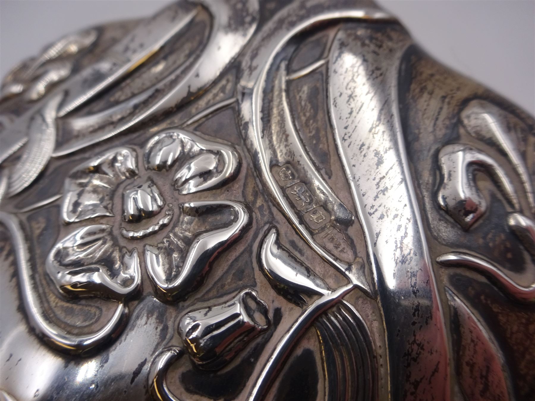 Art Nouveau silver mounted two piece dressing table set, comprising hair brush and hand mirror, each heavily embossed with naturlistic florals and engrved with monograms, hallmarked Walker & Hall, Sheffield 1907