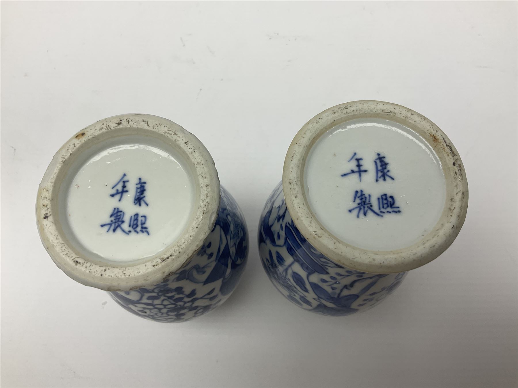 Pair of Chinese blue and white vases, of squat baluster form, each depicting figures holding a ginger jar, with four character Kangxi mark beneath, H13.5cm