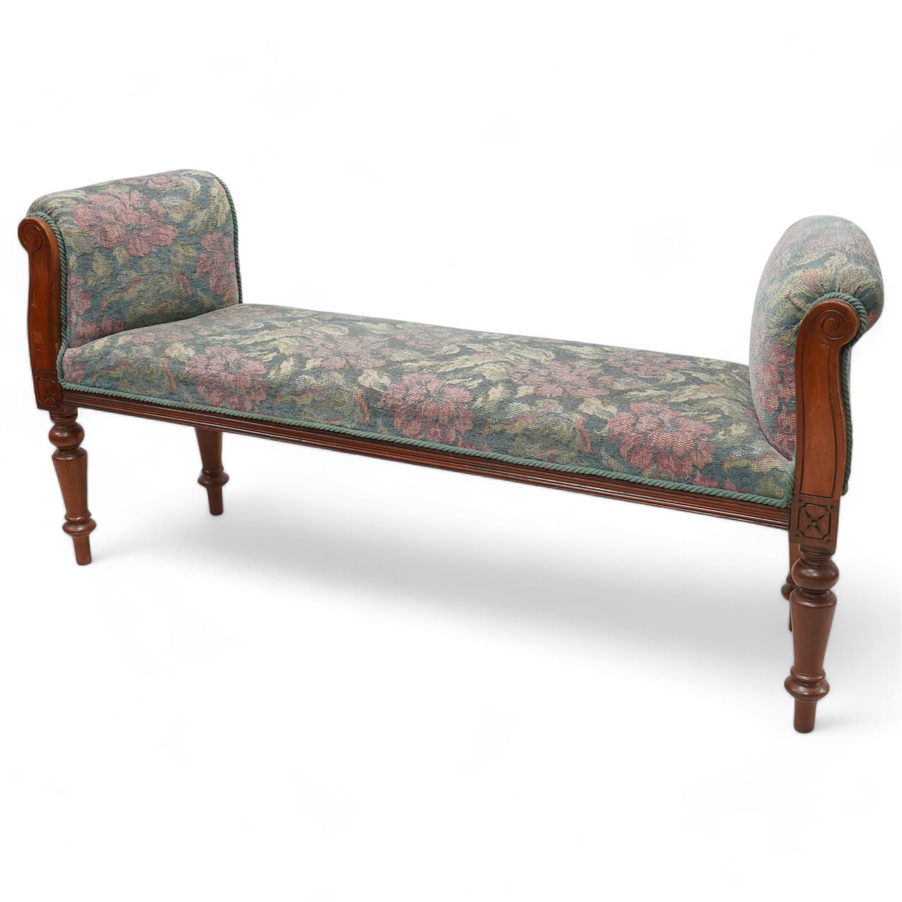 19th century mahogany framed bay window seat of tapered form, rolled arms decorated with carved scrolling, seat and arms upholstered in indigo ground floral patterned fabric, moulded lower rail over turned supports