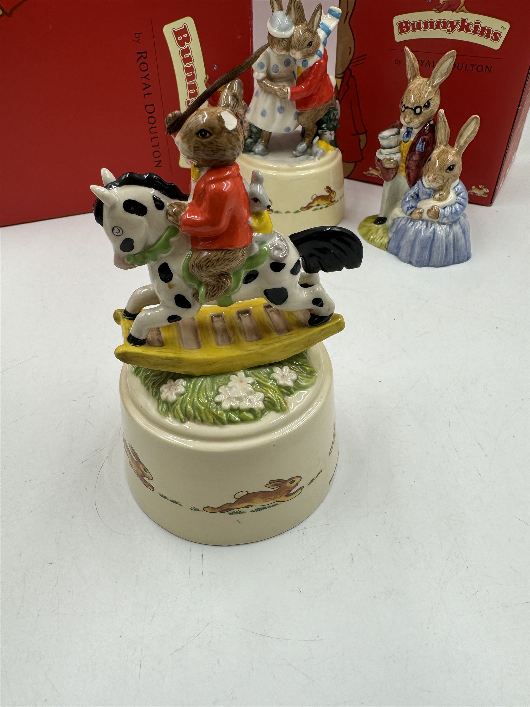 Two Royal Doulton Bunnykins music boxes, comprising Rocking Horse and Winter Waltz together with two Royal Doulton Bunnykins figures Once Upon a Time and Father, Mother & Victoria, all with original boxes  