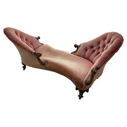 Victorian walnut framed tete-a-tete loveseat, scrolled arm terminals with moulded foliate decoration, buttoned backs and sprung seat upholstered in pale pink velvet, raised on cabriole supports with applied flower heads and scroll feet terminating to ceramic castors