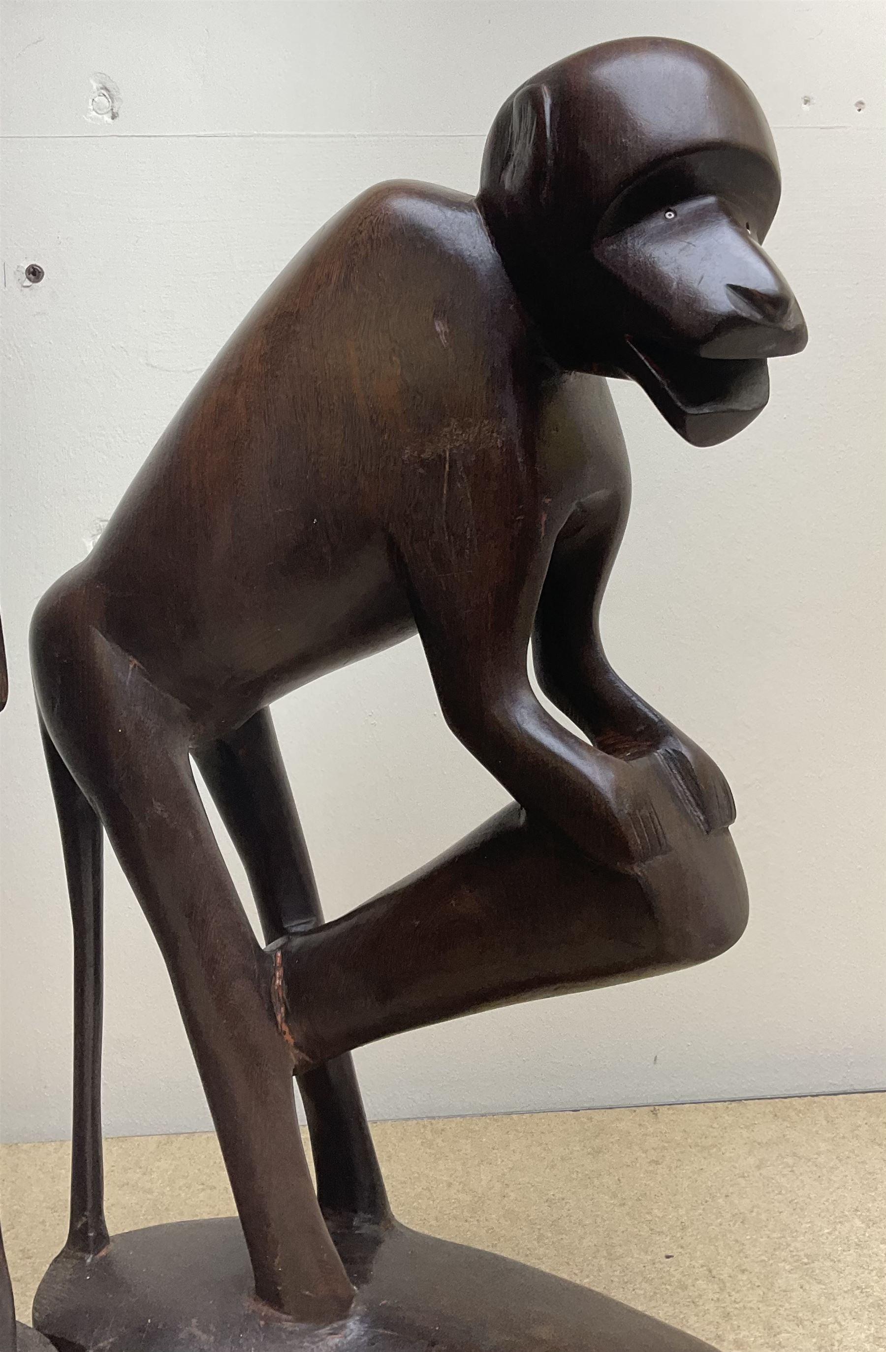 Two African carved hardwood figures, the first carved as a monkey, H43cm, the second as a male figure, H70cm