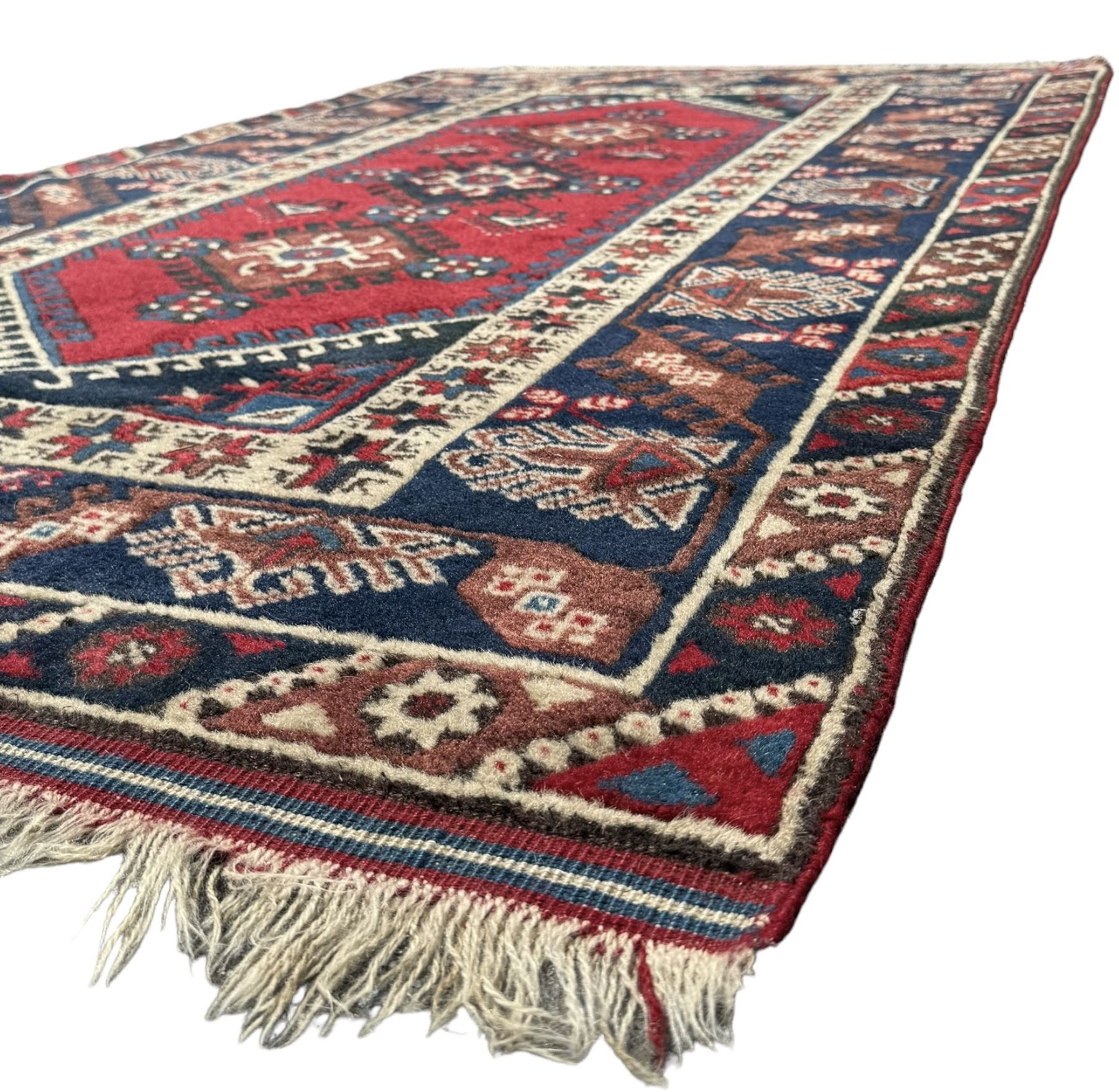 Turkish crimson ground rug, the field decorated with three geometric medallions within a band of star motifs, the main border decorated with stylised plant motifs 