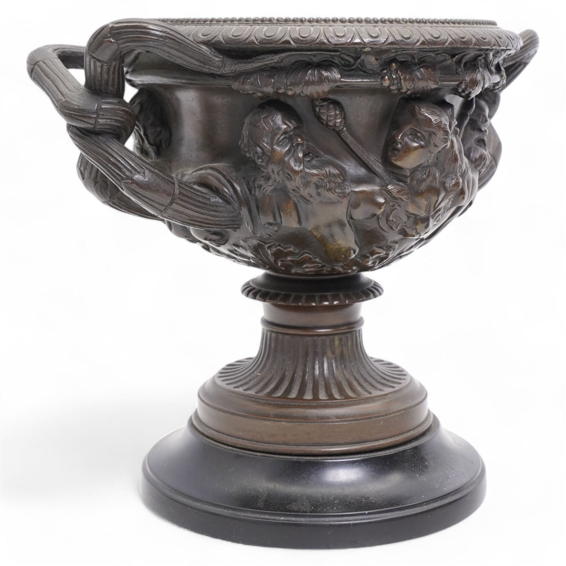 Pair of 19th/ early 20th century bronze 'Warwick' vases, after the antique, of typical form, cast with Bacchic masks and Thyrsus, on a lion pelt-cast ground, with egg and dart and beaded borders and twin reeded bifurcated branch handles, on square marble plinths, H17cm x W20cm