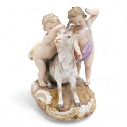 Meissen porcelain group modelled as two cherubs playing with a goat, the oval scroll moulded base heightened in gilt, blue crossed swords, inscribed no. 2454, H10cm, together with a Meissen figure of a young girl and boy, possibly emblematic of autumn, unmarked, (2) Provenance: From the Estate of the late Dowager Lady St Oswald