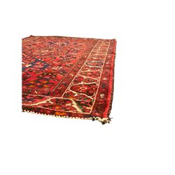 Persian Hamadan rug, red ground with overall geometric design, the field with three extended lozenges, decorated with geometric and stylised flower head motifs, the border and guards decorated with repeating geometric motifs