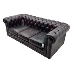 Chesterfield three-seat sofa, traditional shaped upholstered in deeply buttoned dark red leather; together with similar footstool 