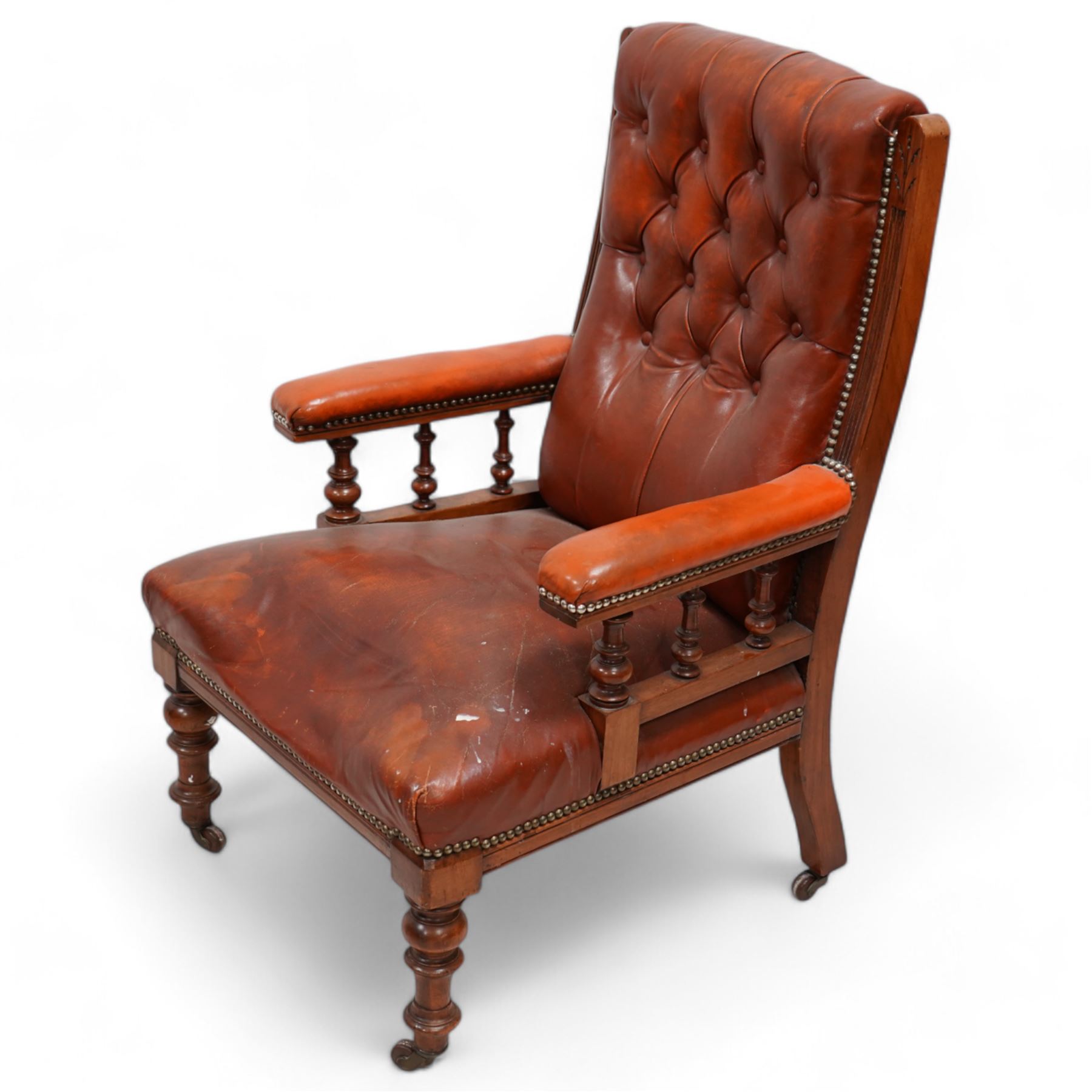 Late Victorian walnut matched two-piece salon suite upholstered in rust buttoned leather - open armchair, reed moulded frame and turned balustrade arm supports, on turned front feet with brass and ceramic castors (W60cm, H92cm, D70cm); nursing chair, fan carved cresting rail, moulded frame, on turned front feet (W58cm, H93cm, D73cm)